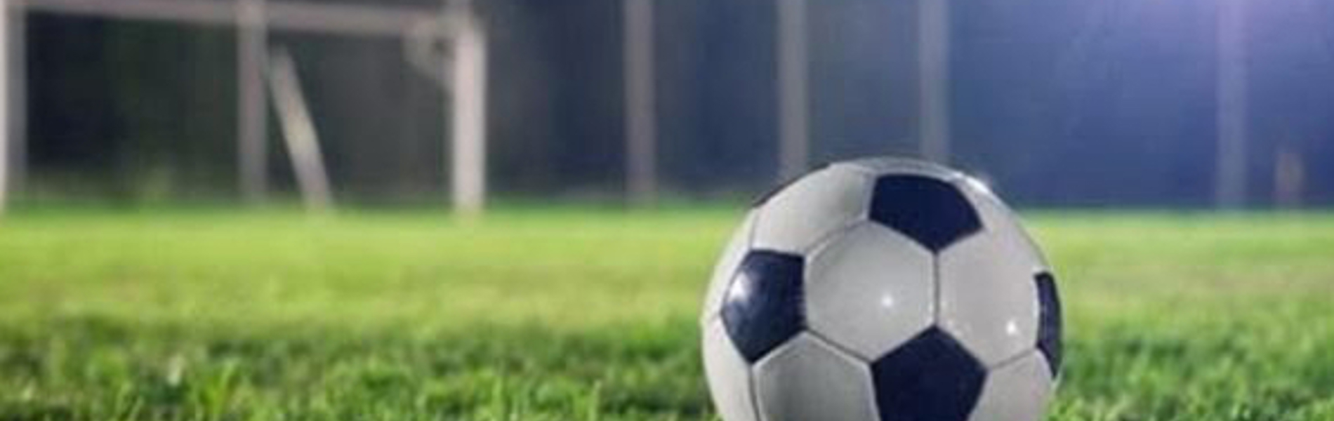 A black and white football sitting on a grass pitch.