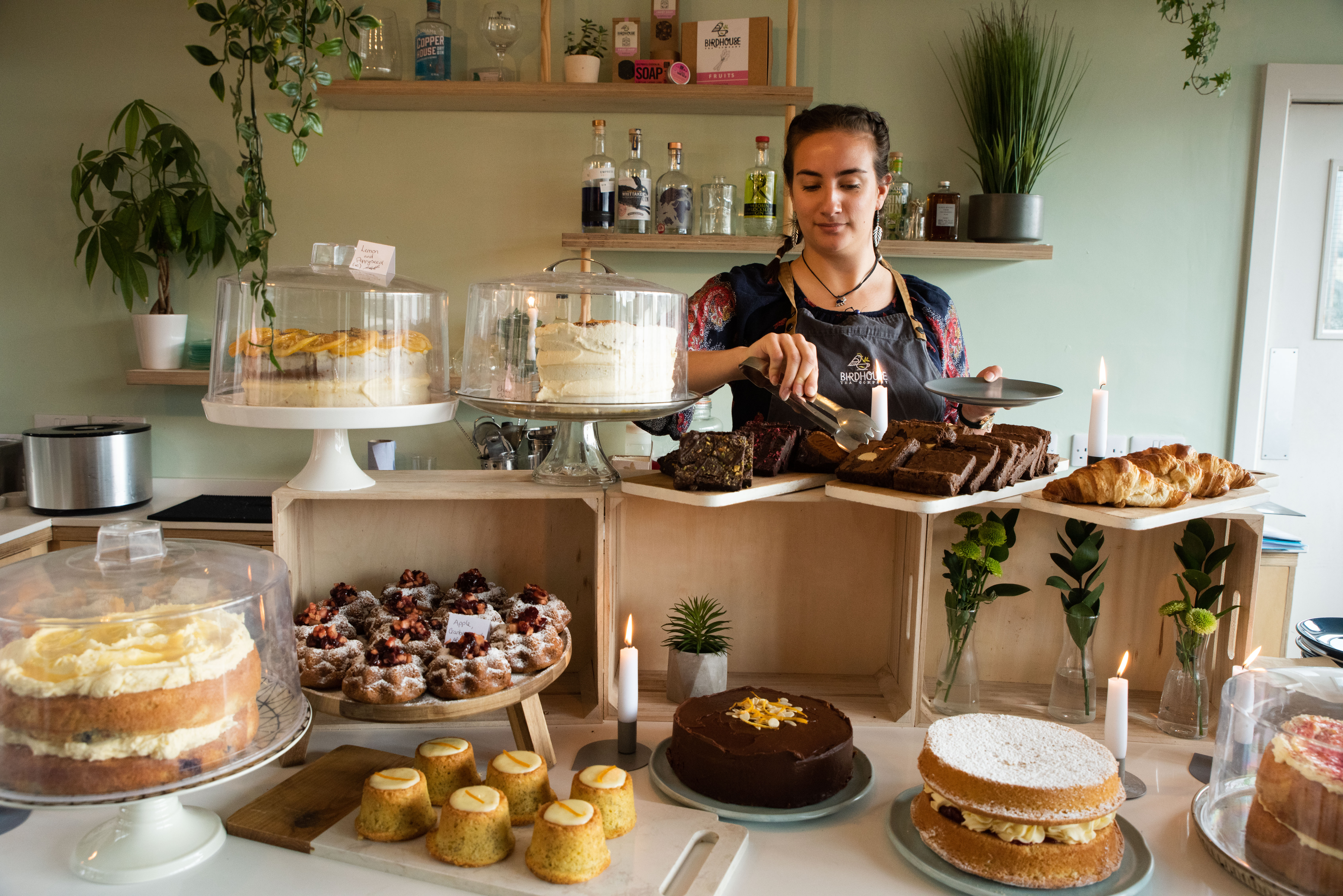 A woman works behind a counter cover in cakes of all different shapes and sizes.