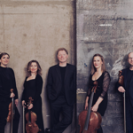 Members of  Ensemble 360 pose against a concrete wall, holding their instruments.