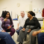 Five people, sat on chairs, are having a discussion.