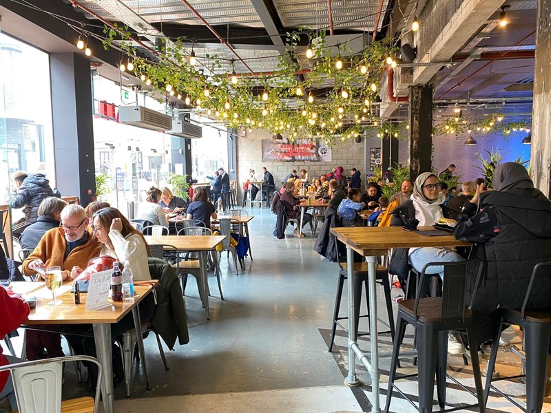 Inside Sheffield Plate, a bright an airy foodhall in Sheffield . There are lots of people sat at tables eating and chatting.