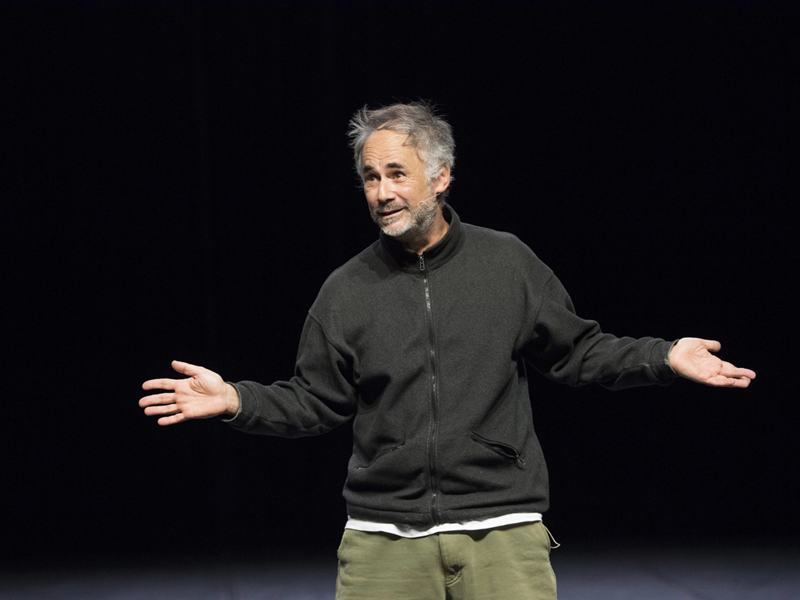 A man standing on a stage with his arms outstretched.