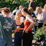 A group of people in a pub garden, enjoying a drink in the sunshine.