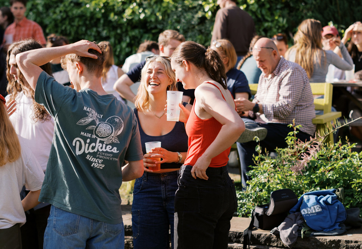 A group of people in a pub garden, enjoying a drink in the sunshine.