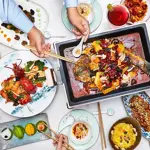 A large table, covered in a white cloth, and filled with plates and dishes of food.