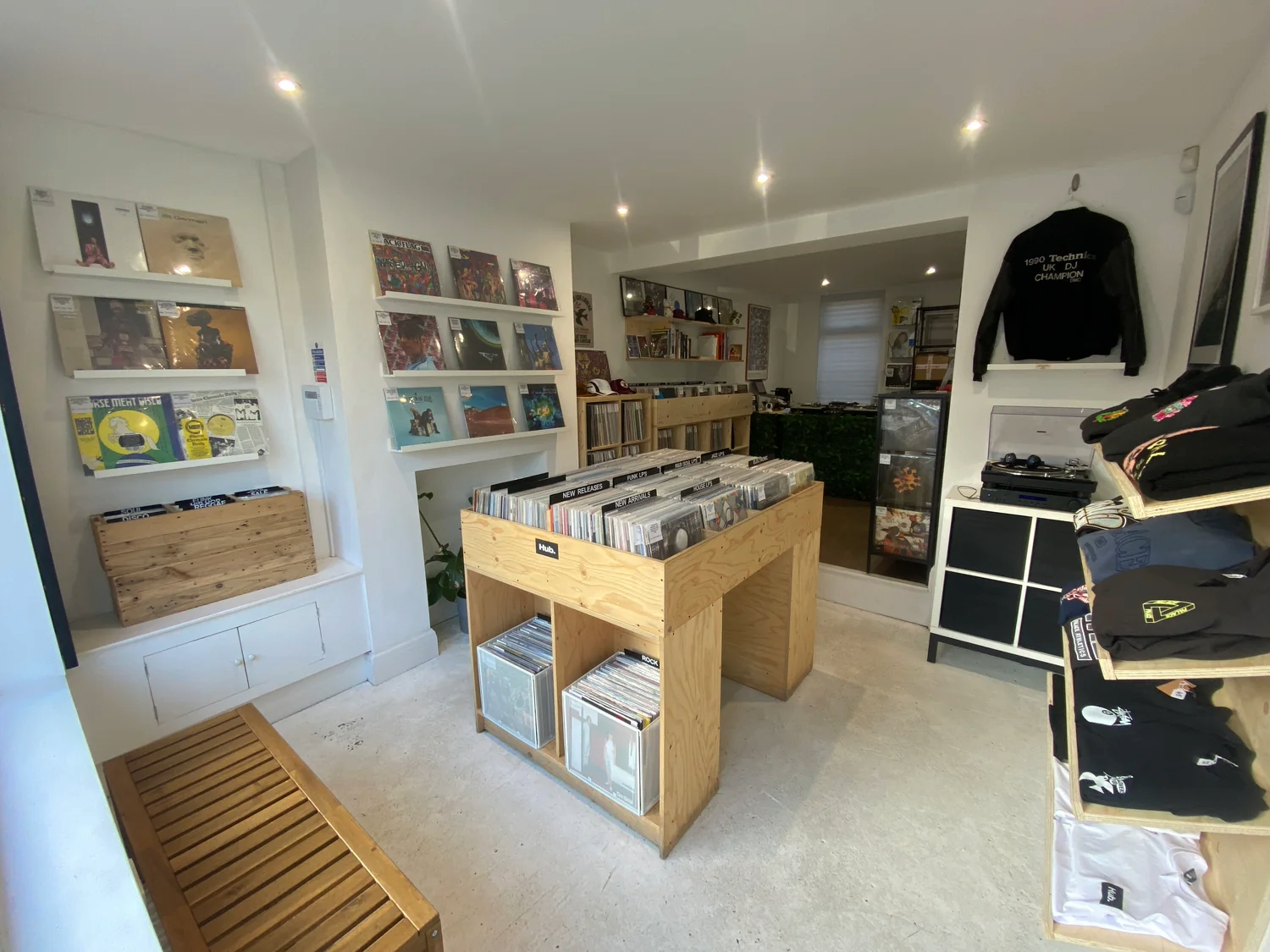 Inside a cosy record shop you can see racks of vinyl and records displayed on the wall. The shop decor is white and minimalist.