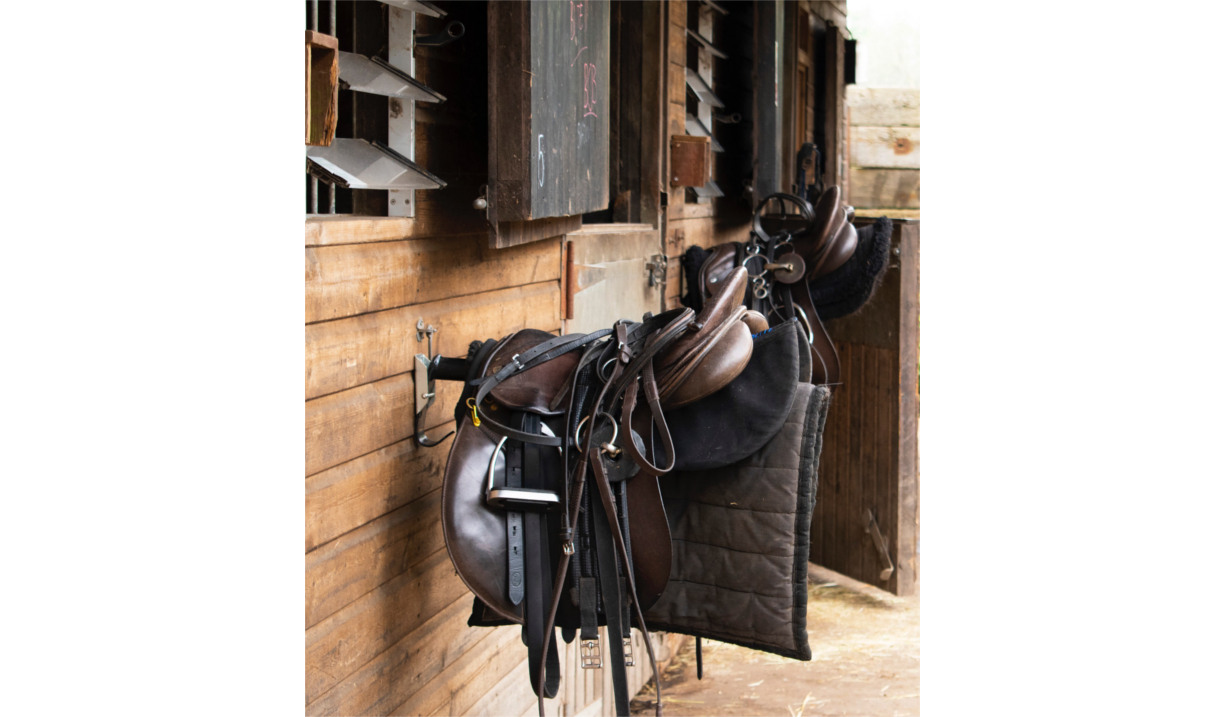 A saddle hanging up at a stable.
