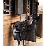 A saddle hanging up at a stable.