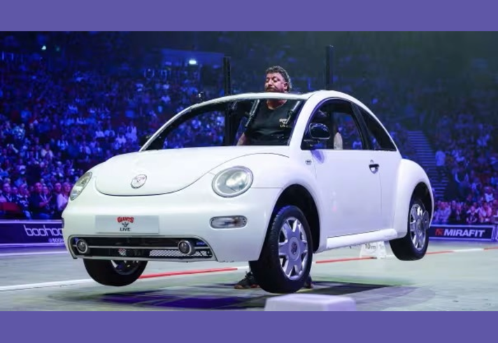 A man lifts up a car in front of an Arena crowd - Britain's Strongest Man 2027