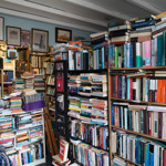 Interior of Porter Book Shop showing tall, densely packed bookshelves filled with a wide variety of second‑hand books. The room is full of stacked books, framed artwork on the walls, and an eclectic, cosy atmosphere typical of a classic used bookshop.