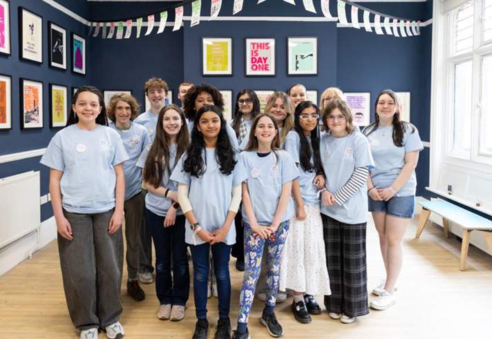 A group of young people standing in the middle of an art exhibition.