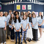 A group of young people standing in the middle of an art exhibition.