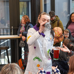 A person in a lab coat is doing fun science experiments with a group of children.