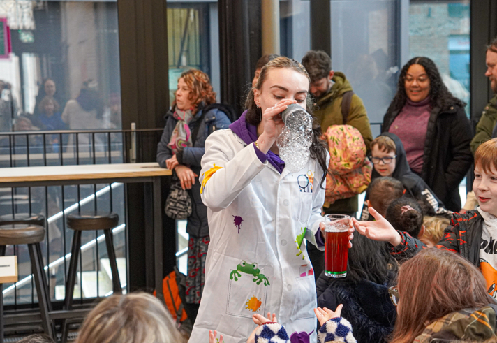 A person in a lab coat is doing fun science experiments with a group of children.
