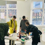 Four people stood round a table, taking part in a print making workshop.
