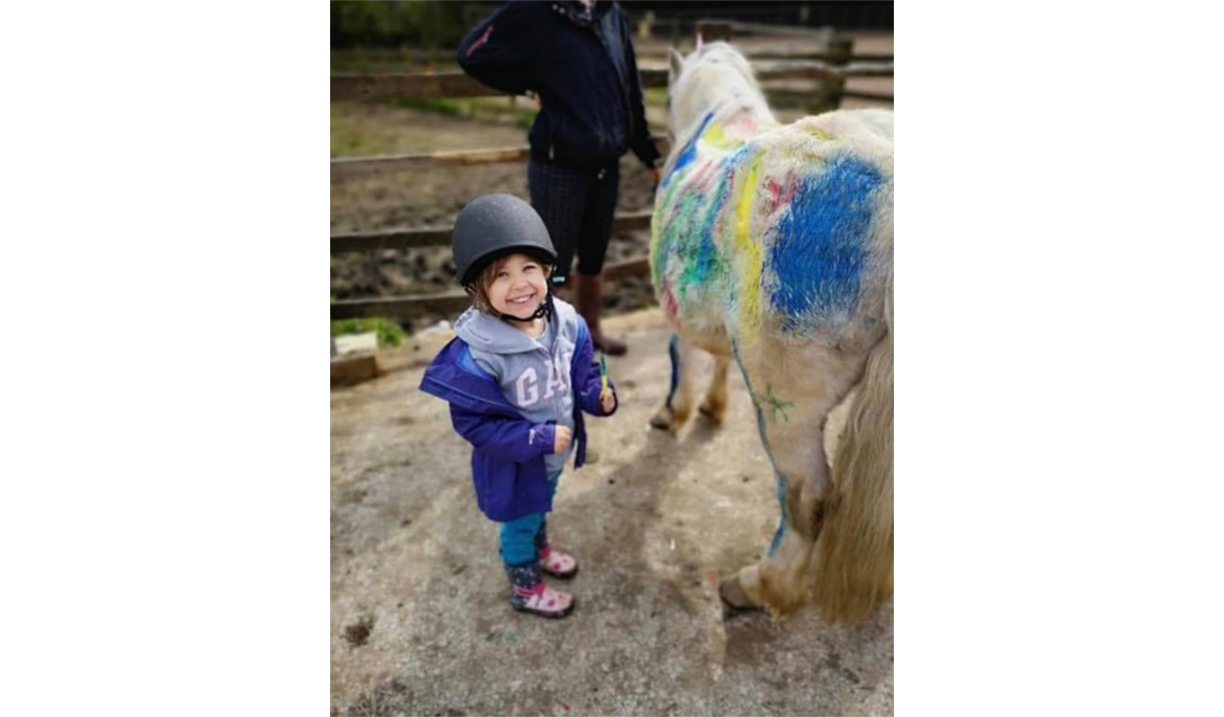 A small child, who is grinning, standing next to a white pont.
