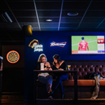 Two people sat at a table having a chat and a drink at The Wildcard Bar & Grill.