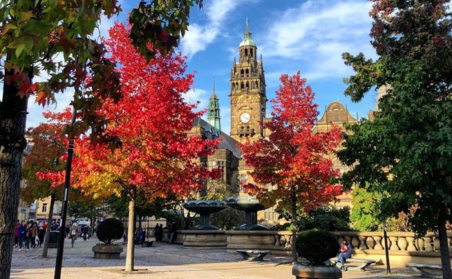 Sheffield Town Hall behind red and green leafy trees in the Peace Gardens