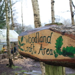 A hand carved wooden sign that reads 'Woodland Craft Area'.