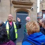 A tour guide gesturing and talking to a tour group.