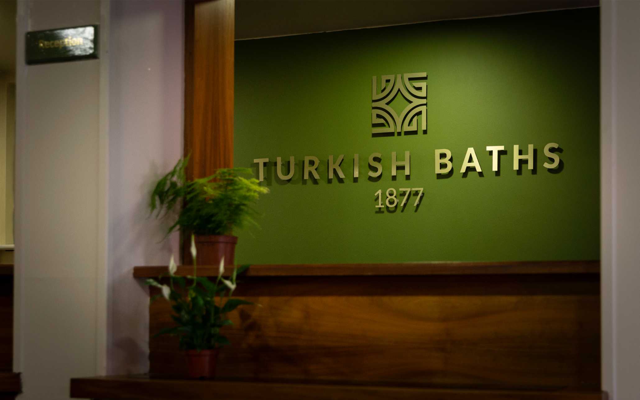 Spa 1877 sign on a wall with plants 