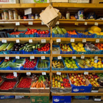 A whole wall of wooden shelving full of organic fruit and vegetables for sale.