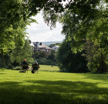 Two people sat in camping chairs, enjoying the sunshine, in Meersbrook Park.