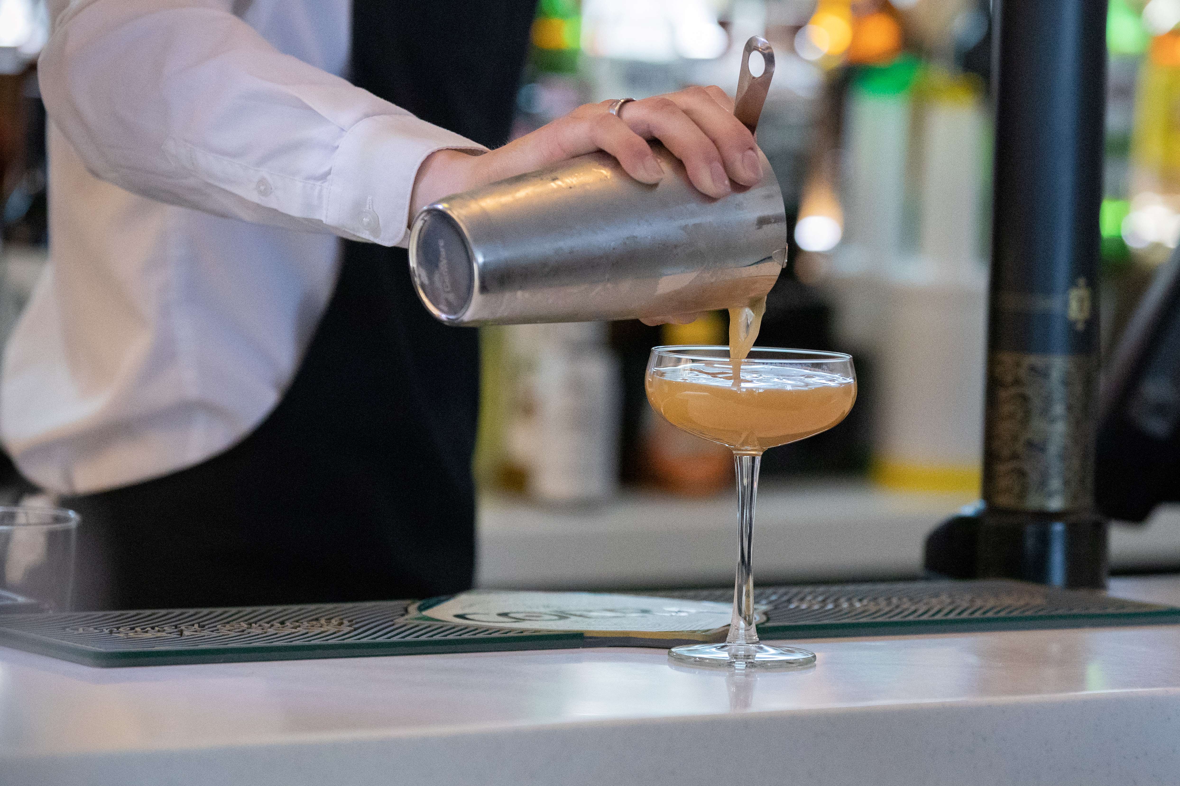 A cocktail being poured into a Champagne glass. 