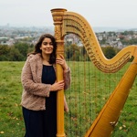 Imogen Garnettand her harp, in a field.