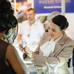 A close-up of a person holding a piece of jewellery for another person to have a look at.