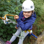 A child abseiling down a rock-face. 