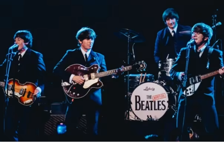 A photograph of The Bootleg Beatles playing live on stage.
