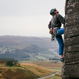  A person, in climbing gear, is climbing up a rock-face. 