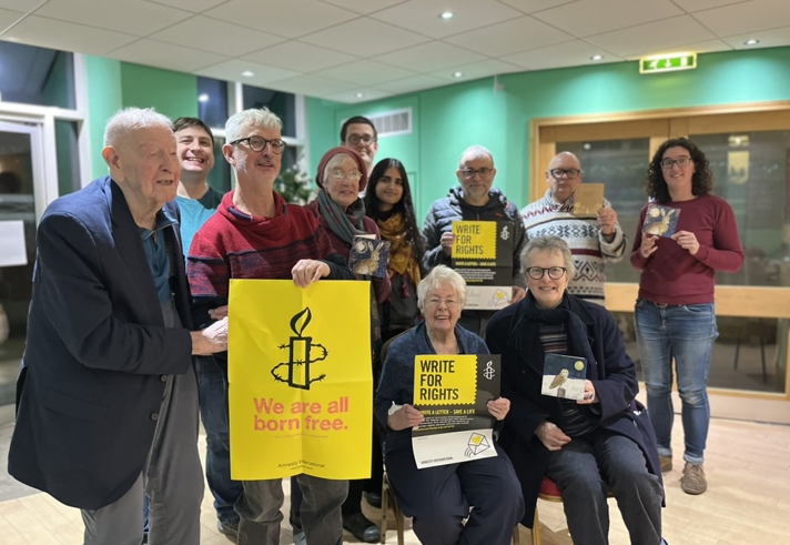 A group of people holding Amnesty International signs and posters.