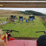 A man and a woman aiming crossbows at targets on a shooting range.