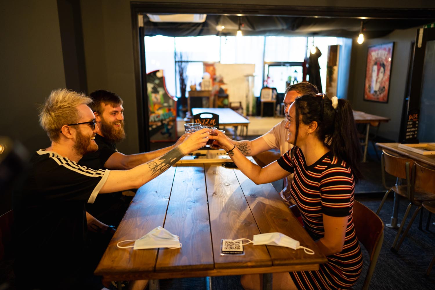Four people are sat at a wooden table, having a drink and enjoying themselves at Escape. 
