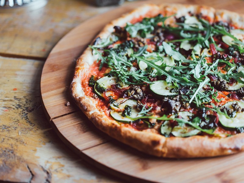 A pizza on a wooden board.