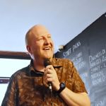 A smiling man holding a microphone.