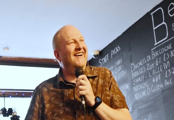 A smiling man holding a microphone.