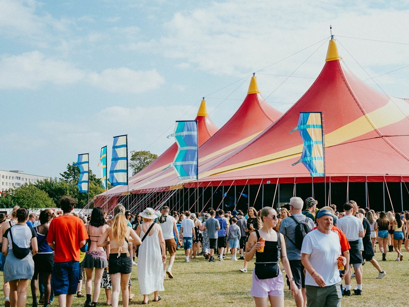 Crowds walk towards the bright red tent of the T'Other stage at Tramlines