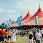 Crowds walk towards the bright red tent of the T'Other stage at Tramlines 
