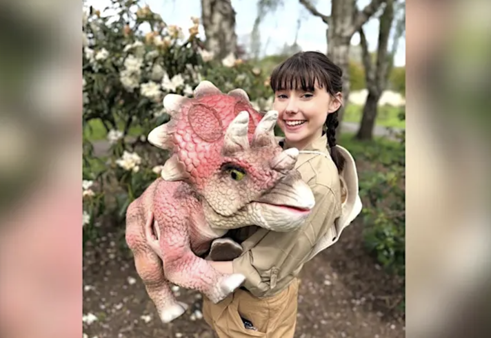 A person holding a large cuddly dinosaur.