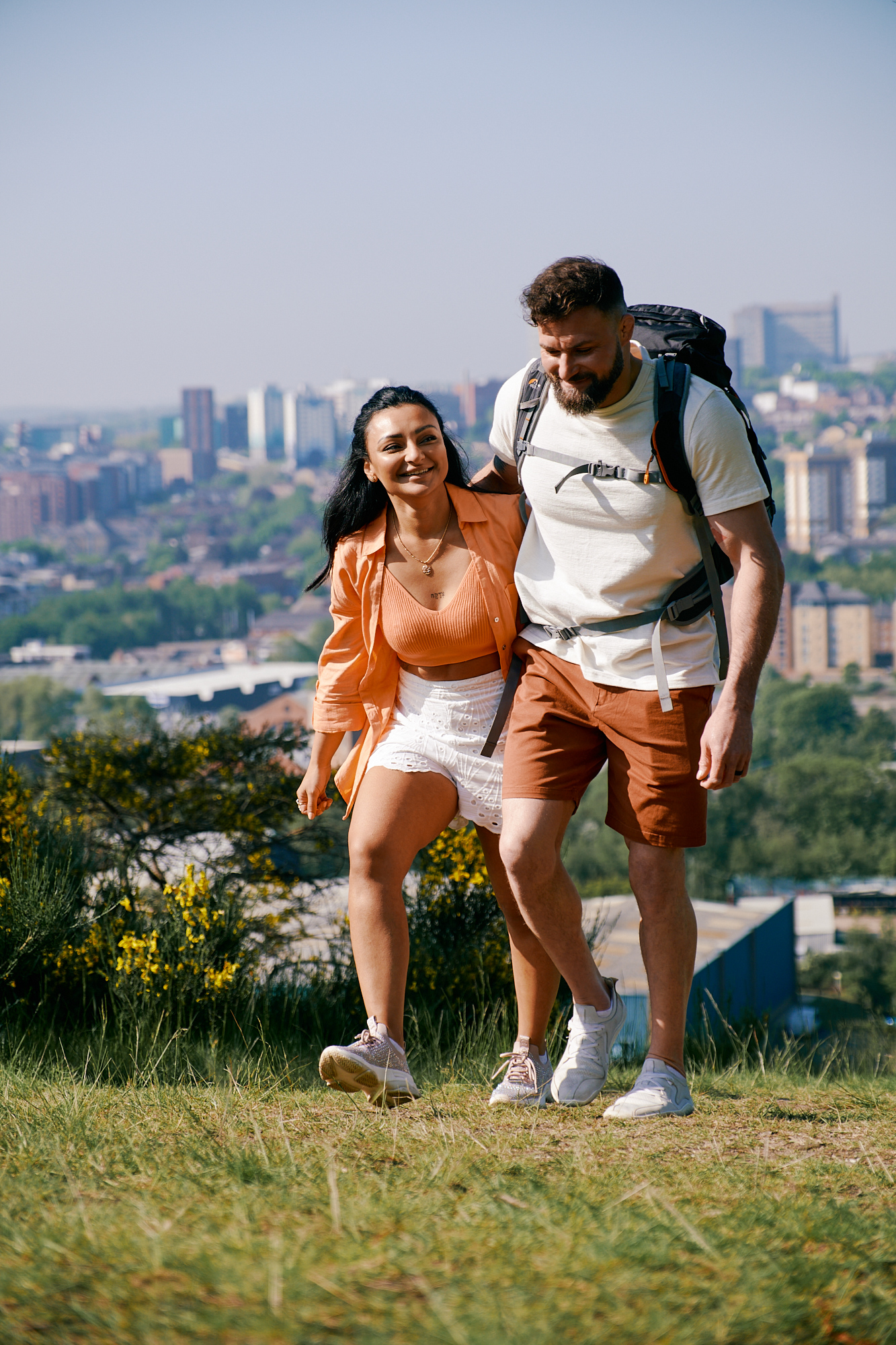 Couple walking up a hill at Parkwood Springs in Sheffield, with cityscape in the background.