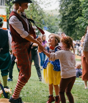 Two children dancing with a clown at the Tramlines Festival.