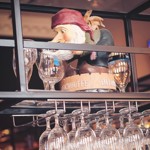 A model of a pirate hiding on am overhead glass rack, above the bar.