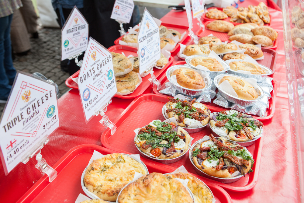 An array of baked and pastry items laid out a long a table front of a stall 