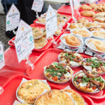 An array of baked and pastry items laid out a long a table front of a stall 