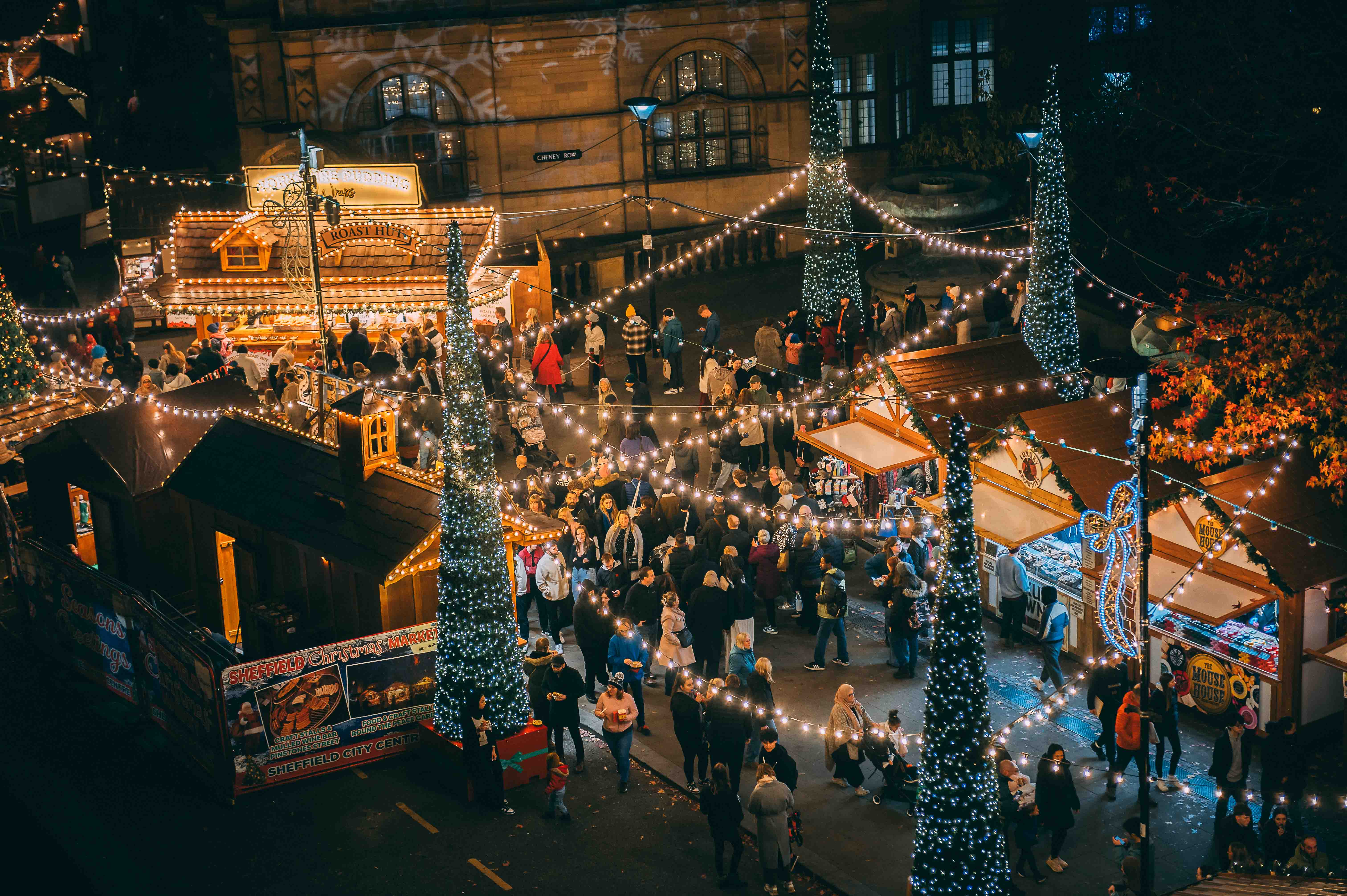 Looking Down On Log Cabins At Sheffield Christmas Market. Everywhere is lit up with Christmas lights and strings of fairy lights.