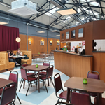 Interior shot of the Neepsend Social Club & Canteen with tables and chairs in the foreground and the bar and booths in the background