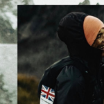 A person in an orange hat and black coat is laughing.